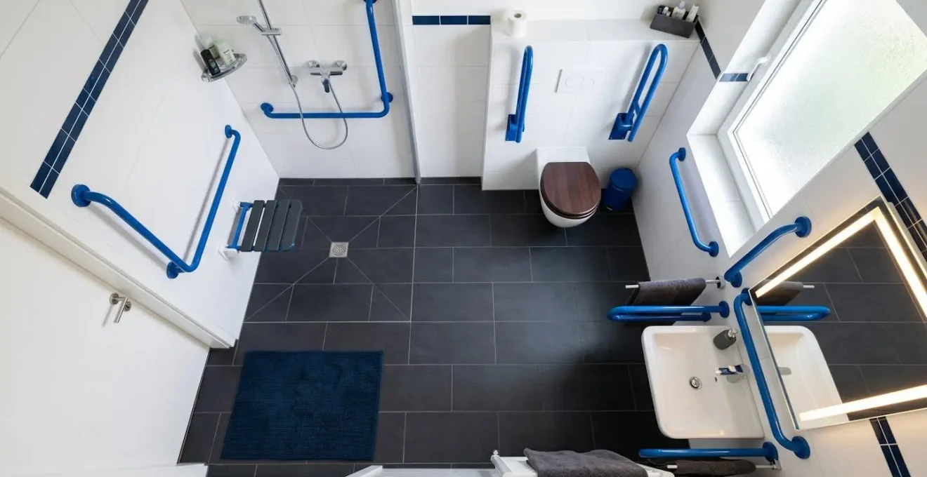 Vue d'ensemble d'une salle de bain adaptée montrant l'aménagement sécurisé avec barres d'appui et contrastes visuels